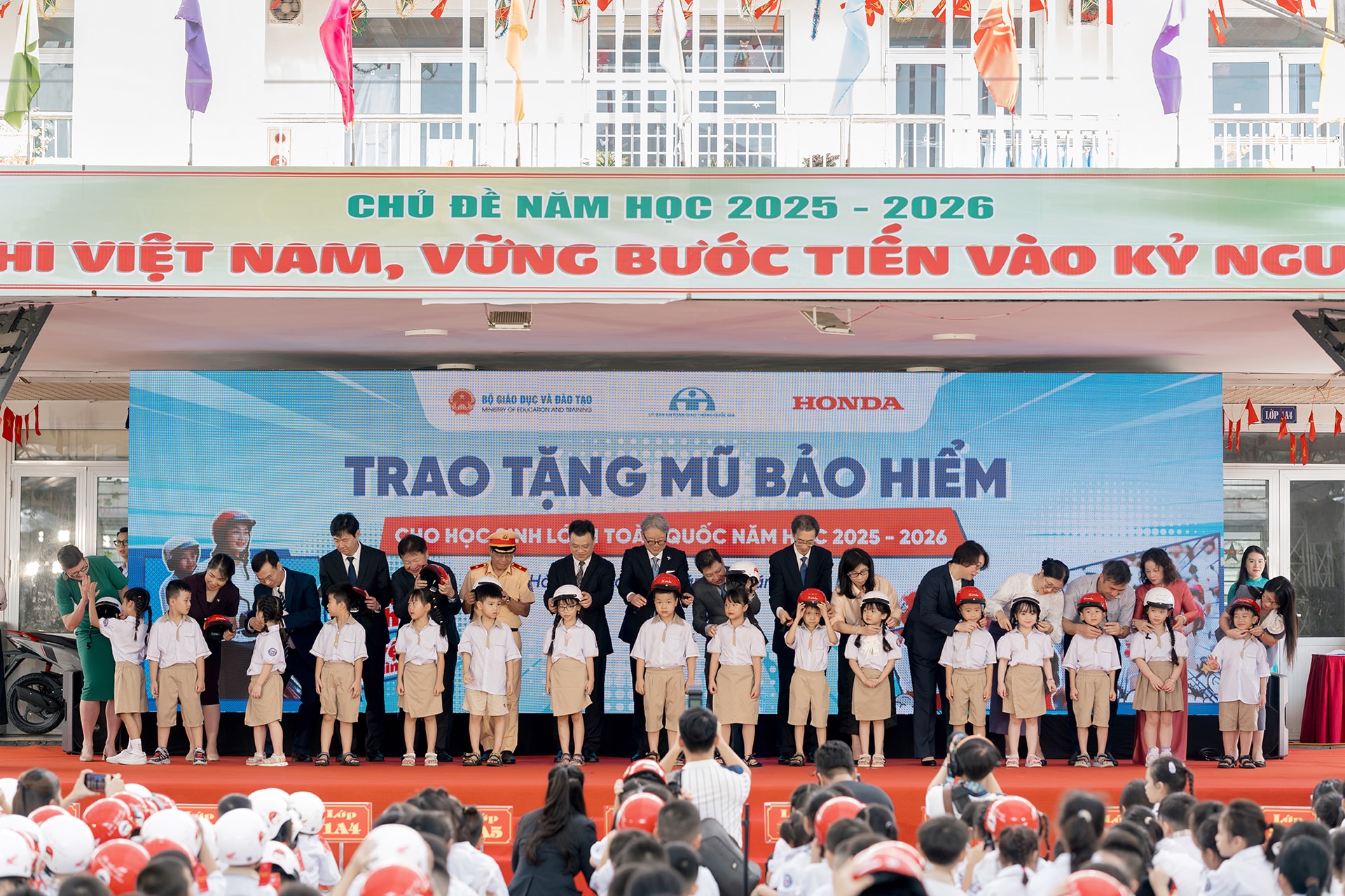 Đại diện tập đoàn Honda, lãnh đạo Ủy ban An toàn giao thông Quốc gia, Cục Cảnh sát giao thông và Bộ Giáo dục và Đào tạo trao mũ bảo hiểm đạt chuẩn cho học sinh lớp Một tại Trường Tiểu học Vạn Bảo, Hà Nội.