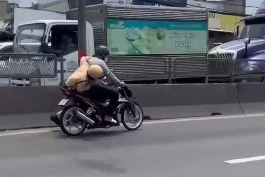 Người đàn ông lái xe máy chạy trên đường, mặc cho CSGT bám yên xe